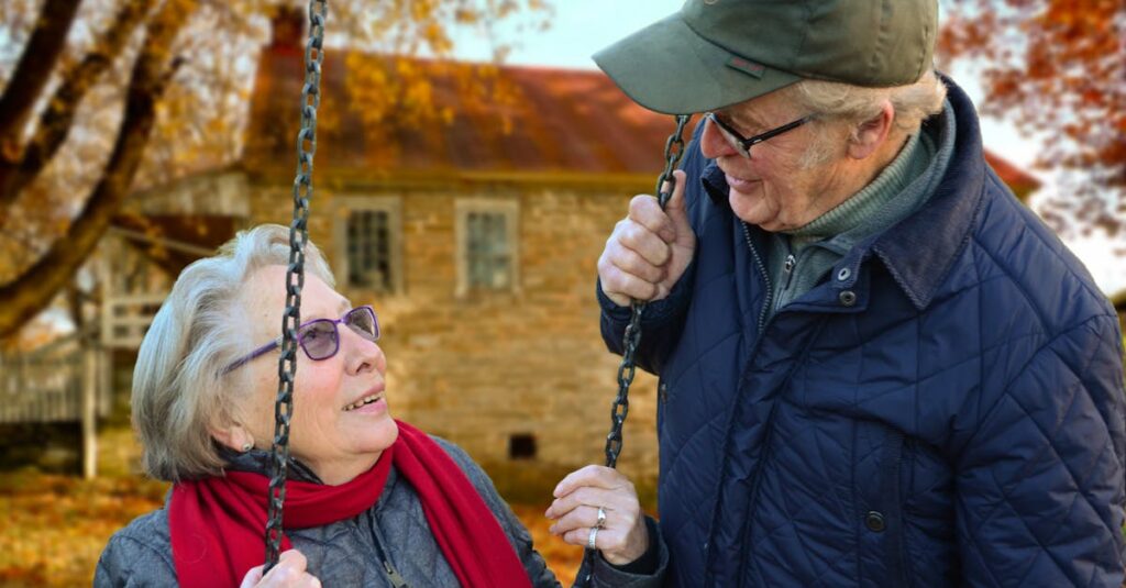 A happy elderly couple sharing a joyful moment on a swing in autumn setting.